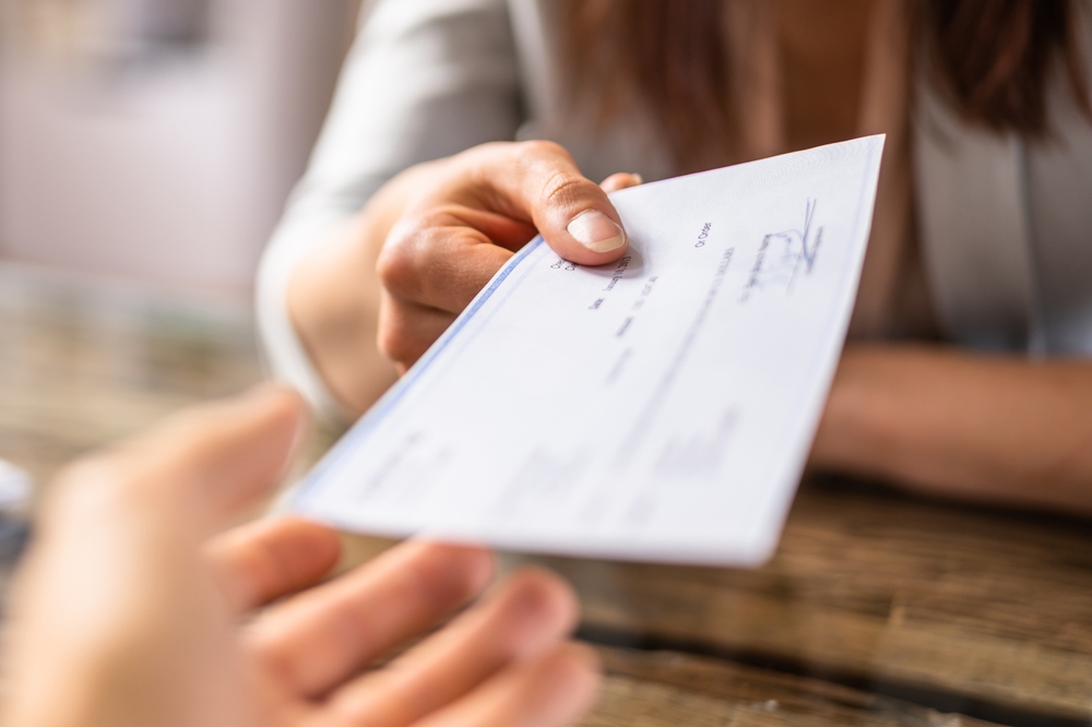 Close-up of someone receiving a paycheck.