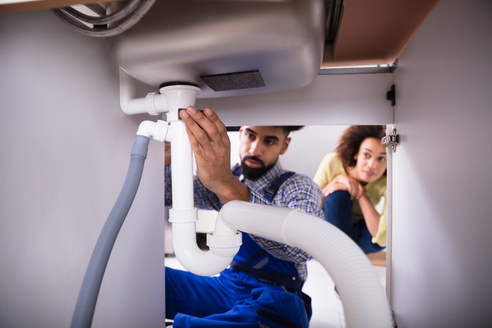 Woman watching plumber repair sink