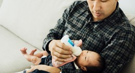 Asian father, feeding milk to a 10-day-old newborn baby girl