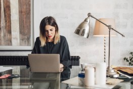 Pretty Caucasian woman sitting at her office deks and working on her laptop.