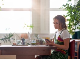 Woman working from home on her laptop computer, flexible hours freelancer modern lifestyle lens sun flare