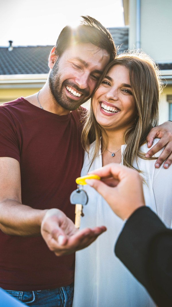 Happy couple receiving keys from realtor.