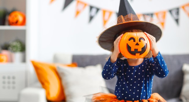 happy laughing child girl in witch costume to halloween