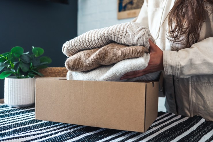 Woman putting sweaters in box to donate.