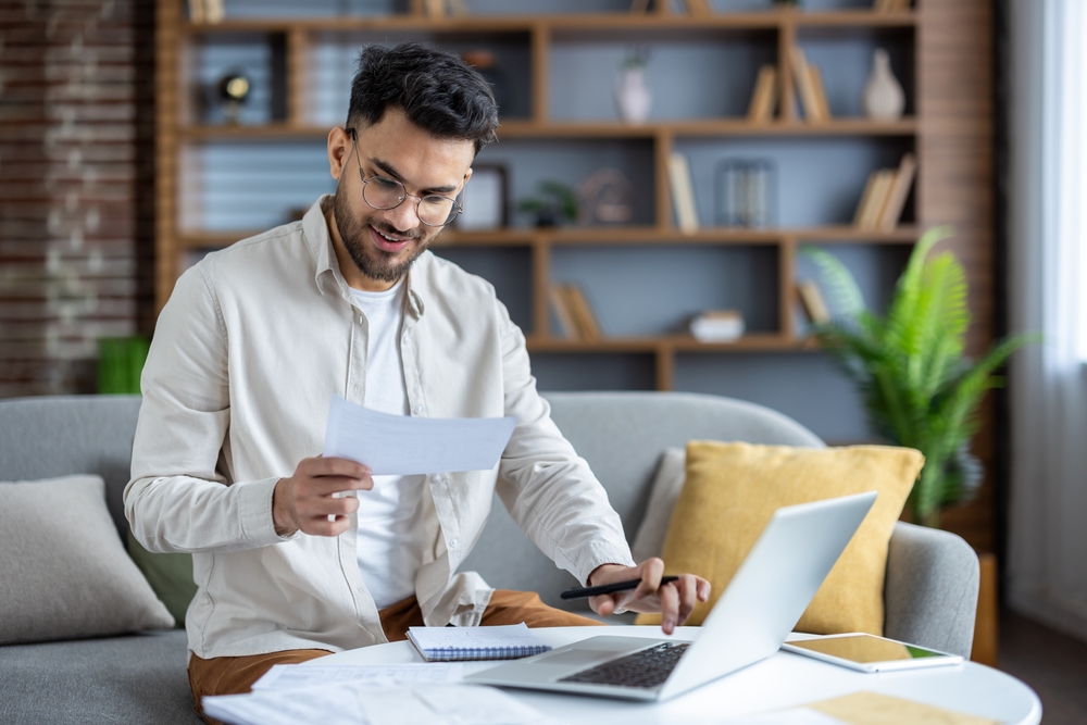 Man sitting on the couch doing taxes.