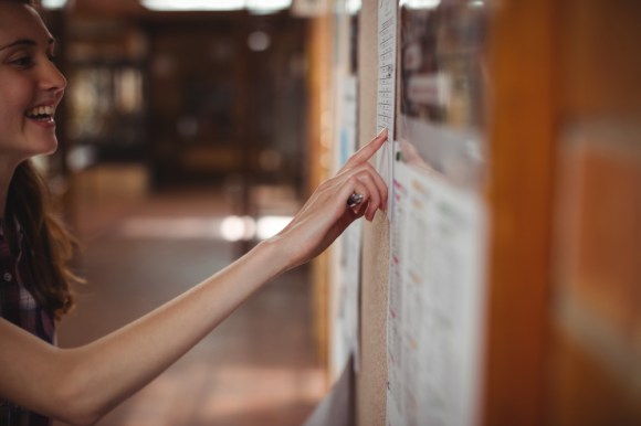 Close up of a woman checking a bulletin board.