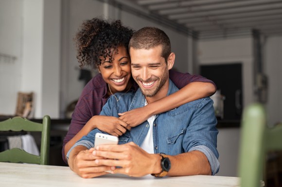 Couple smiling and looking at phone.