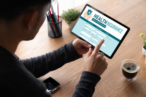 Close-up of a man holding a tablet reviewing a health insurance policy.
