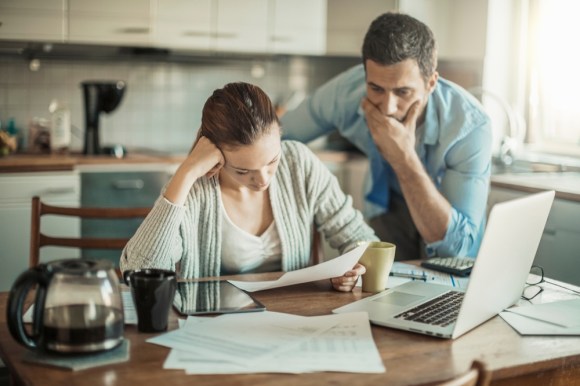 Couple going over finances with stressed expressions.