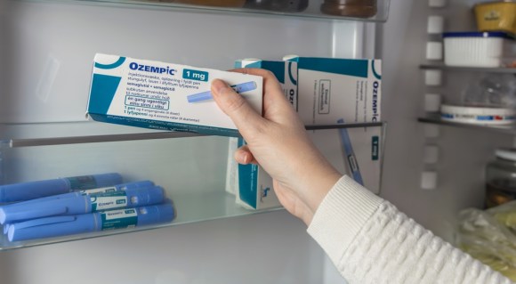 Woman grabbing box of Ozempic from a medicine cabinet.