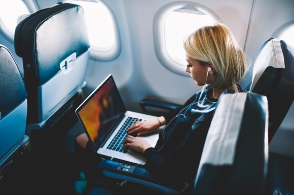 Woman working on laptop in airplane.