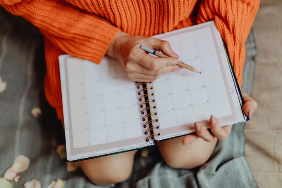 Woman holding a monthly planner in her lap.