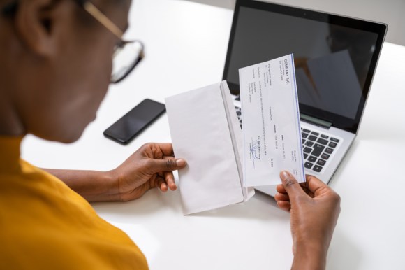 Woman sitting at desk opening paycheck.