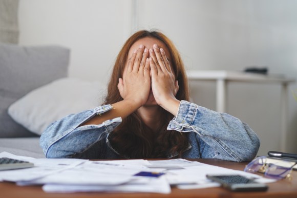 Woman looking stressed with bills in front of her.
