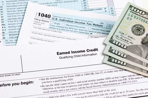 Earned income tax credit form with hundred dollar banknotes laying on top of the form.