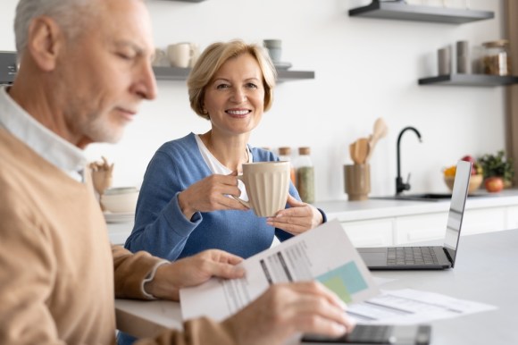 Senior couple reviewing documents together while having coffee