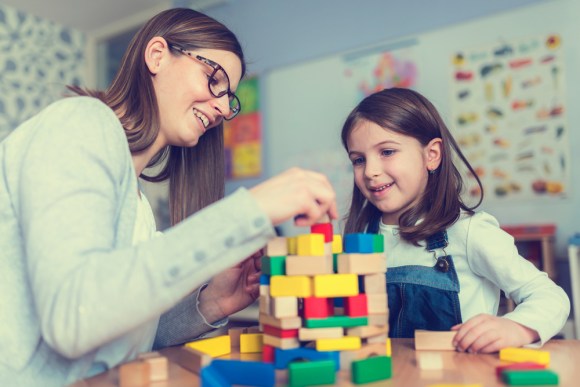 Nanny playing with a little girl with blocks.