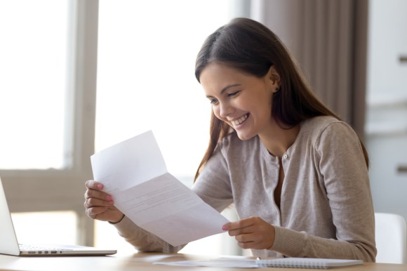 Woman looking at a document with a smile on her face.