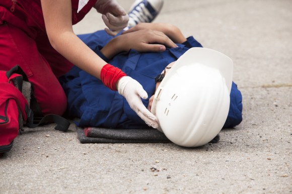 Injured worker lying on the ground with a hard hat.