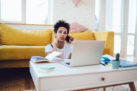 Young entrepreneur on the phone while working from home in front of her laptop.