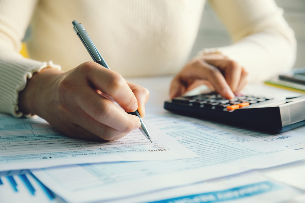 Closeup woman filling form of Individual Income Tax Return.