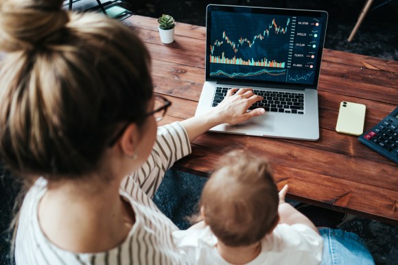 Woman online trading with a baby on her lap.