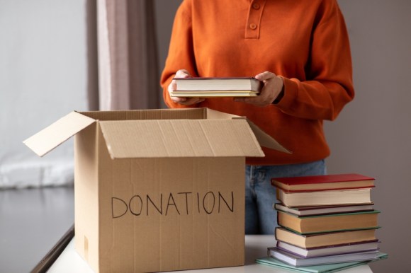Woman packing a box of books to donate.