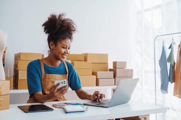 Young Black business owner working at a desk using a laptop.