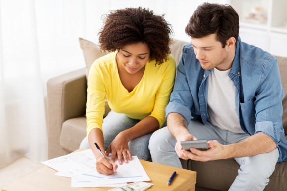 Couple calculating finances together on a couch.