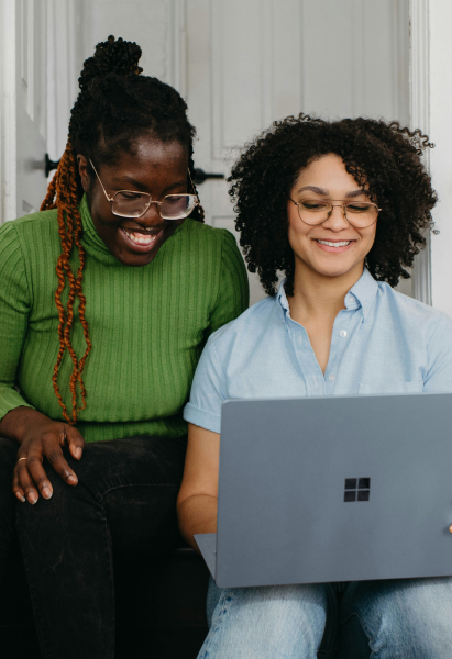 Two gen z people looking at a laptop doing taxes