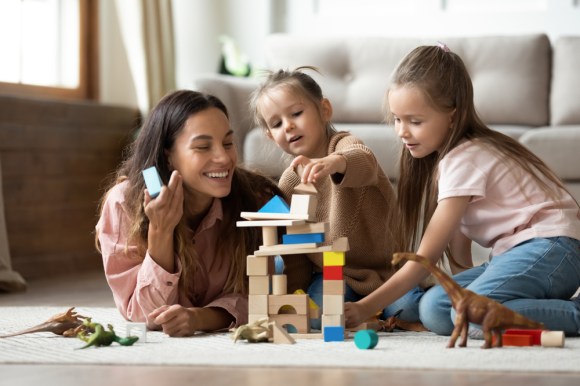 Nanny playing with blocks with two young girls.