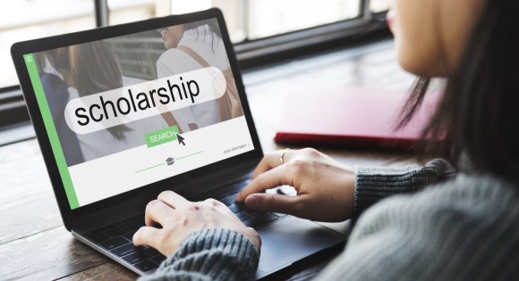 Young woman searching for scholarships online.

