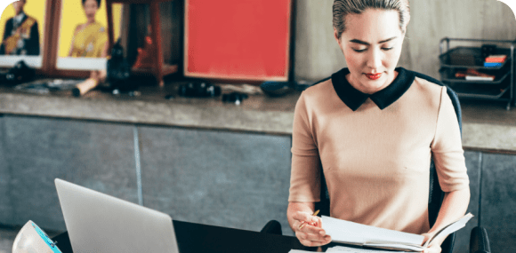 Photo of a woman looking over paperwork at her desk