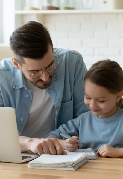 dad helping daughter with school homework, sitting together at table