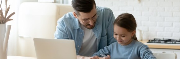 dad helping daughter with school homework, sitting together at table