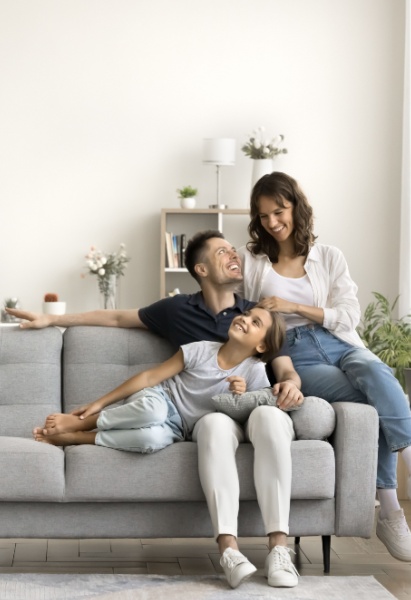 Happy young parents and child sitting and relaxing on sofa