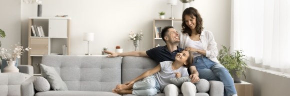 Happy young parents and child sitting and relaxing on sofa